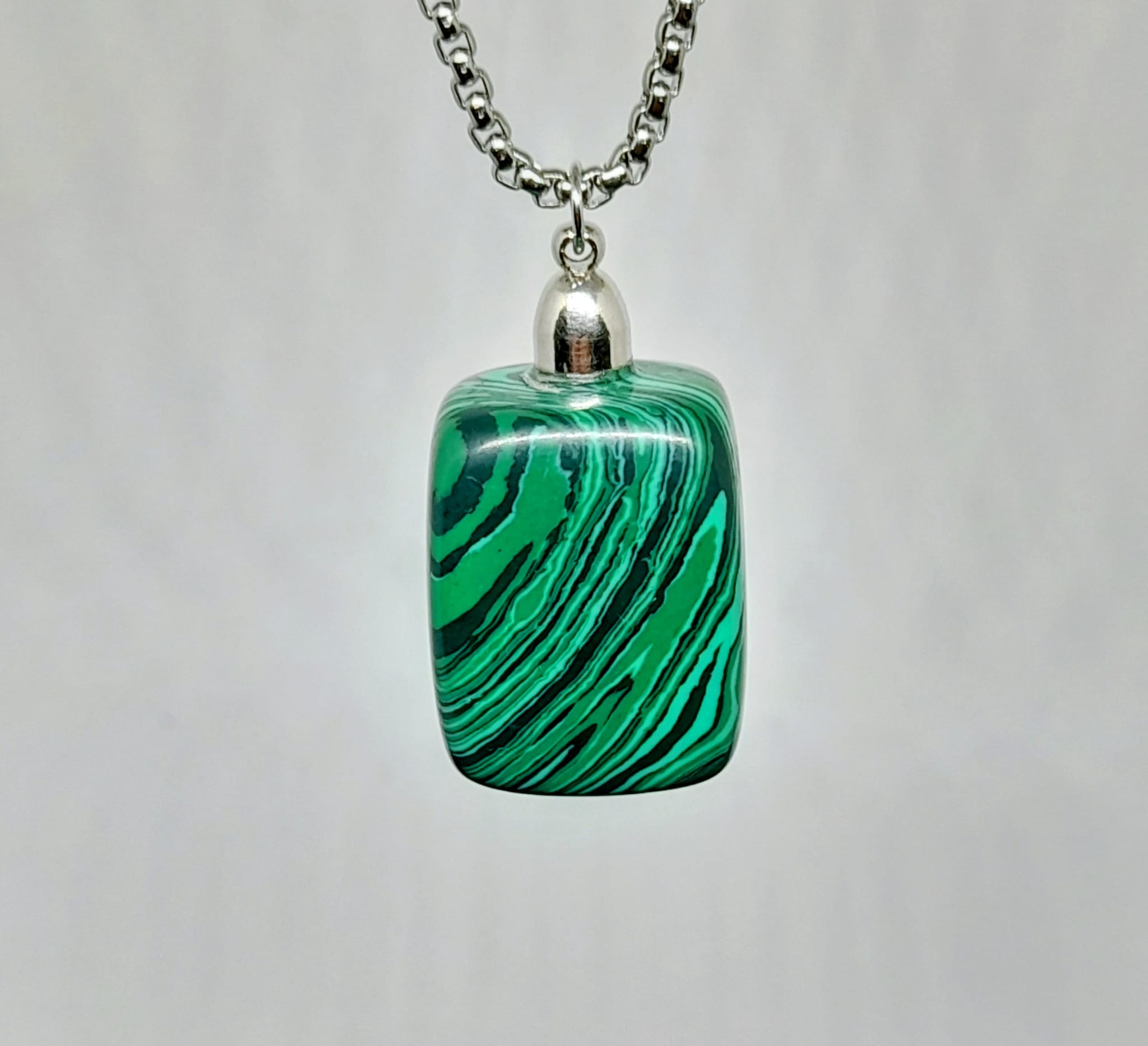Natural malachite stone pendant with emerald green swirling pattern on a silver-tone rolo chain