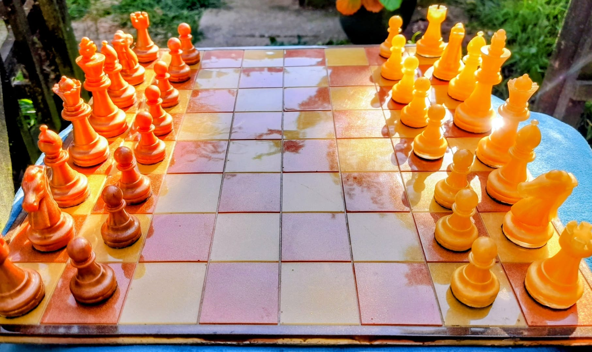 Full view of amber resin chess set with orange and yellow pieces facing off on glittery board